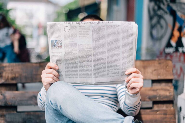 A person sitting on a bench reading a newspaper